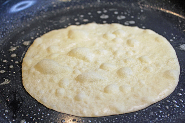 Tortilla in skillet cooking first side