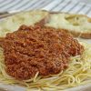Close up shot of spaghetti sauce piled on top of pasta.