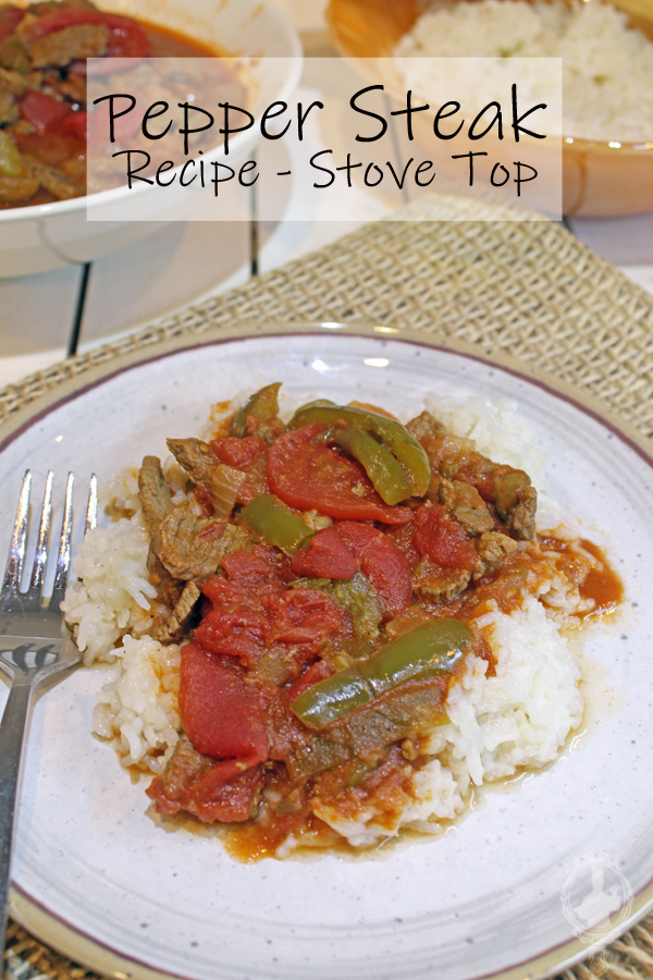 A plate of pepper steak on top of a bed of rice.