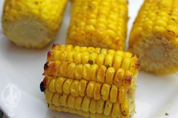 Close up of a serving plate of baked corn on the cob, ranch style.