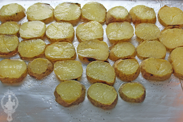 Sliced potatoes on a baking sheet with oil.
