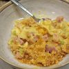 Close up of ham and noodle casserole in a bowl with a spoon.