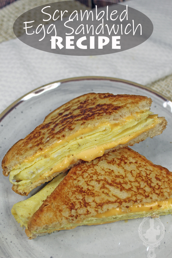A scrambled egg sandwich cut in half on a plate ready to dig in.