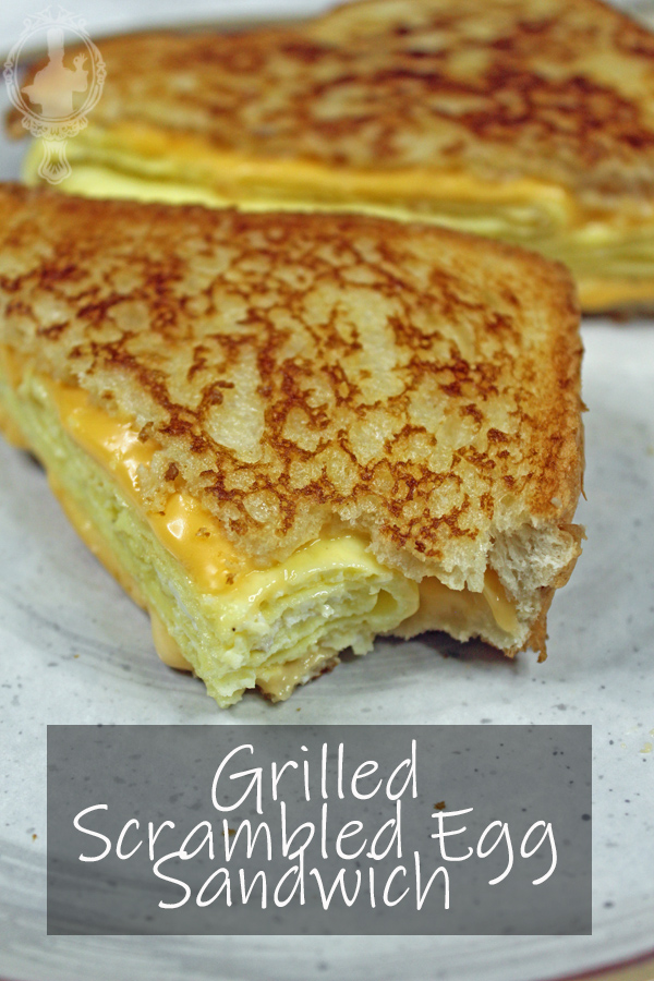 Half of the scrambled egg sandwich with a bite missing.