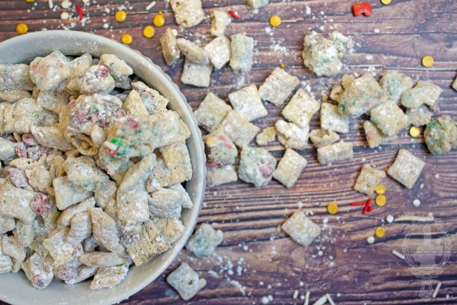 A bowl of Christmas Muddy Buddies with some spilled out around the bowl.
