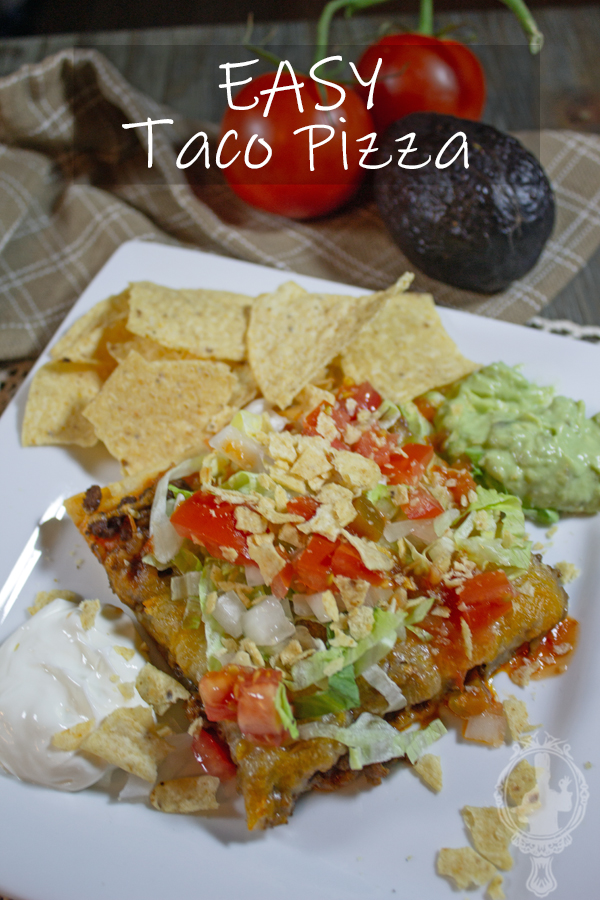 Angled view of a square piece of pizza with tomato, onion and lettuce on top. Guacamole, Sour Cream and Chips on the side.