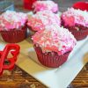 Direct view of 5 valentines day coconut cupcakes with pink icing and coconut sprinkled on top.