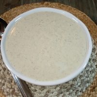 Ovehead view of a serving bowl with country gravy with a ladle on the side.