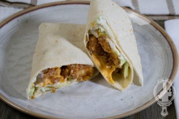 Two halves of a popcorn chicken wrap.