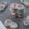 A stack of chocolate covered nutter butters, with scattered cookies around the stack.