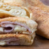 A few slices of the ham and swiss roll up in front with the rest of the loaf behind it.