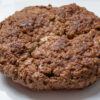 Close up of a stuffed burger with a little bit of cheese peeking through a crack.