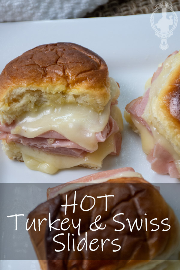 Three turkey and swiss sliders on a plate.