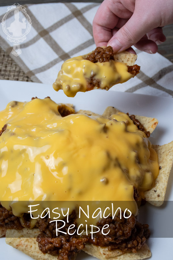 Angled, Close up of Sloppy Joes Nachos with a chip with sloppy joes and cheese ready to bite into.