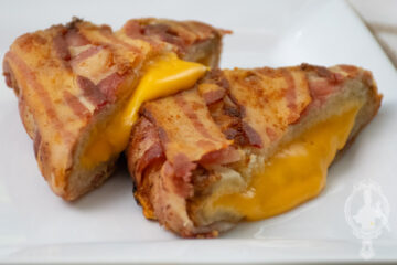 Close up view of two halves of the bacon wrapped grilled cheese.
